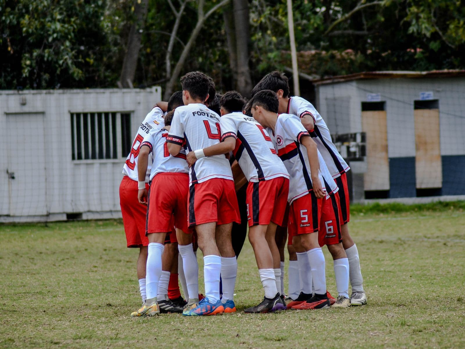 A youth team huddled together on the field before a game